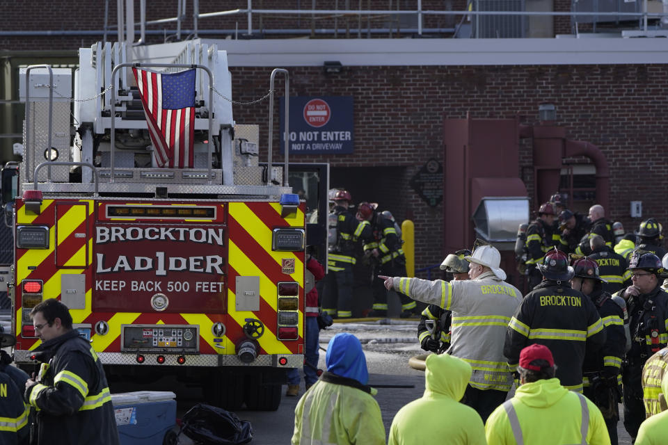 Firefighters stand near a ladder truck near an entrance to Signature Healthcare Brockton Hospital, Tuesday, Feb. 7, 2023, in Brockton, Mass. A fire at the hospital's electrical transformer forced an undetermined number of evacuations Tuesday morning and power was shut off to the building for safety reasons, officials said. (AP Photo/Steven Senne)