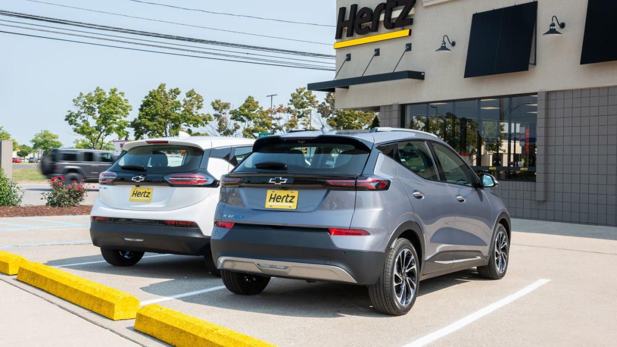 a summit white 2023 chevrolet bolt ev and a gray ghost metallic 2023 chevrolet bolt euv parked in front of a hertz rental location in michigan hertz will begin taking deliveries of the chevrolet bolt ev and bolt euv in the first quarter of 2023