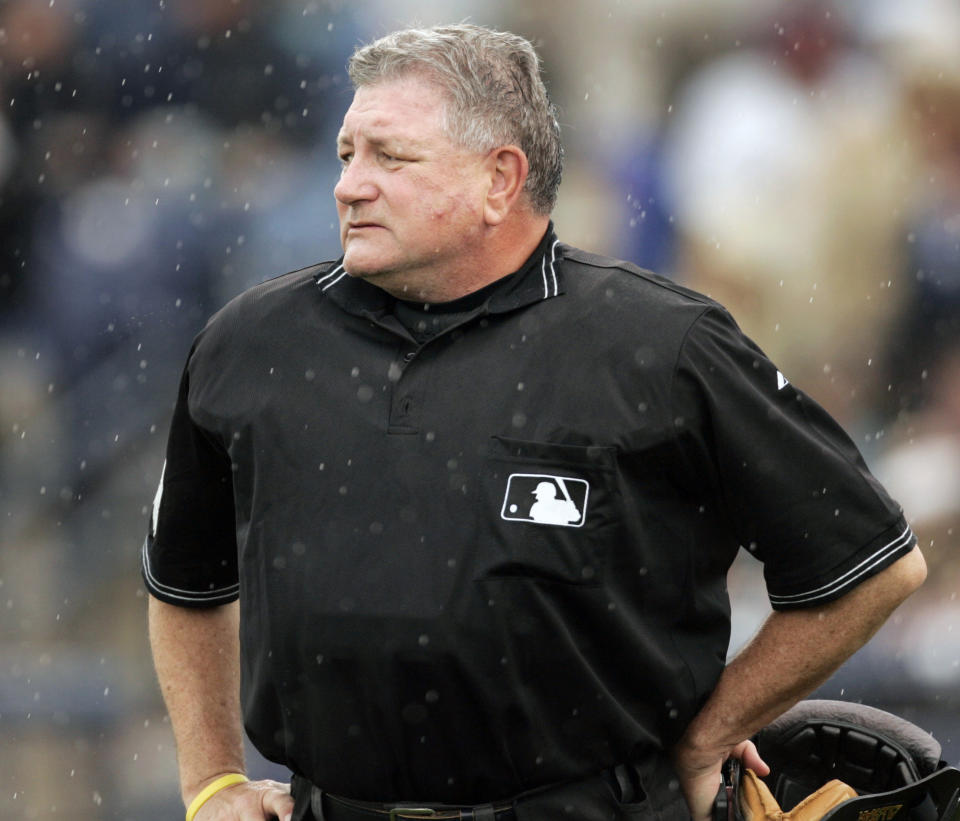 FILE - In this March 21, 2006, file photo, home plate umpire Rick Reed watches the grounds crew cover the infield during the third inning of a spring training game between the Arizona Diamondbacks and the Seattle Mariners in Peoria, Ariz. Reed, whose career as a big league umpire spanned three decades and included two All-Star games and a World Series, has died. He was 70. (AP Photo/Orlin Wagner, File)