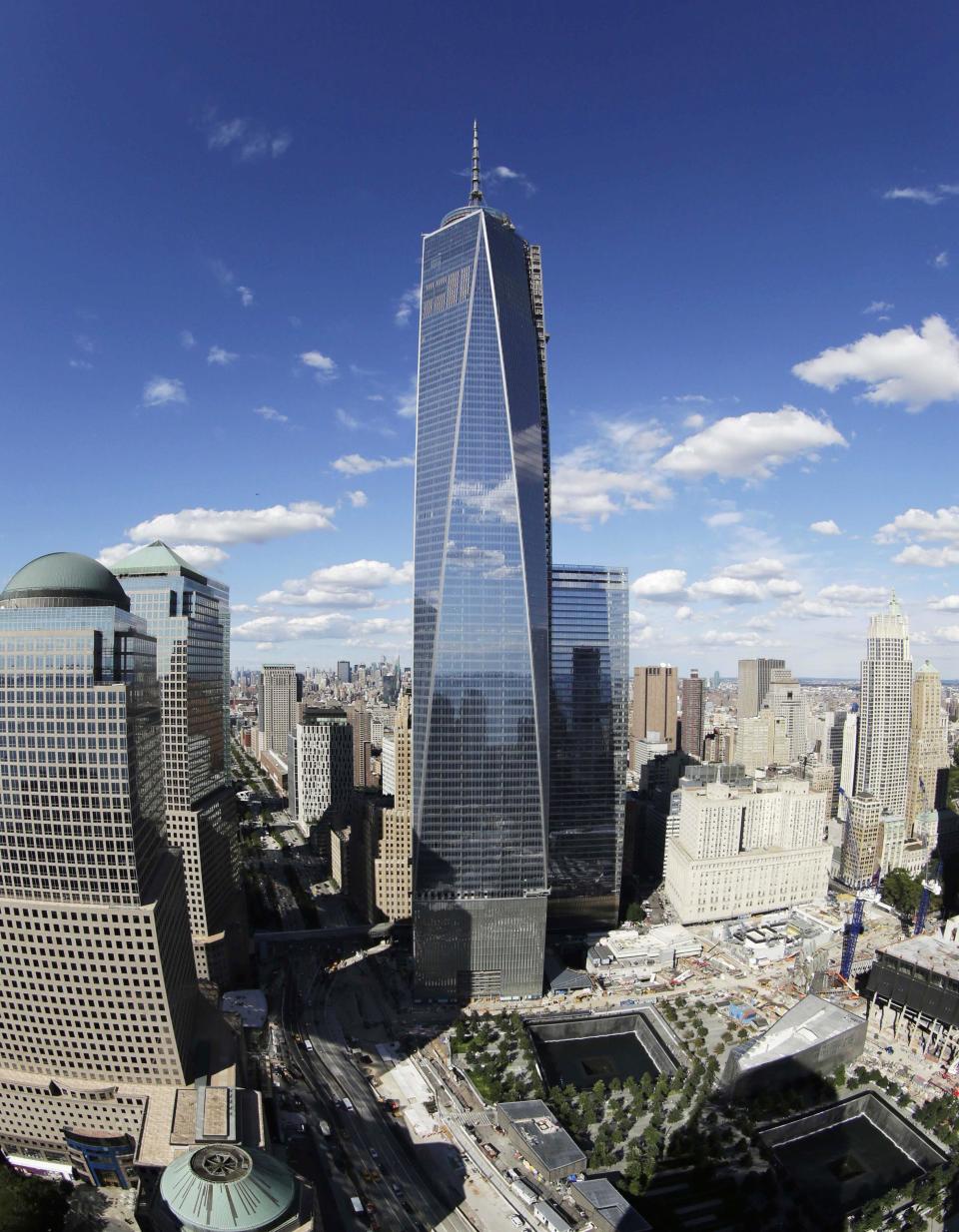 FILE - In this Thursday, Sept. 5, 2013, file photo taken with a fisheye lens, One World Trade Center, center, overlooks the wedge-shaped pavilion entrance of the National September 11 Museum, lower right, and the square outlines of the memorial waterfalls in New York. The long-awaited museum dedicated to the victims of the Sept. 11 terror attacks will open to the public at the World Trade Center site on May 21, officials announced Monday, March 24, 2014. (AP Photo/Mark Lennihan, File)