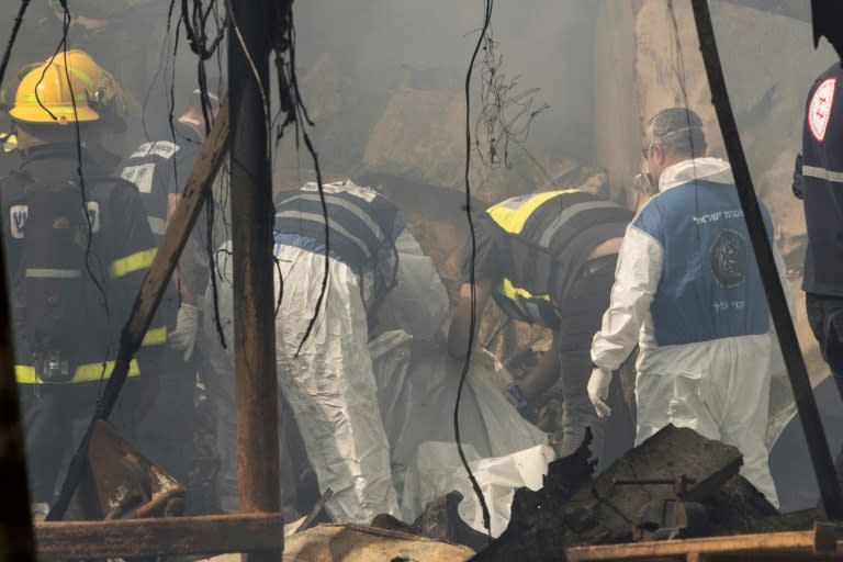 Rescue workers inspect a body after a fireworks warehouse blaze in the Israeli village of Porat on March 14, 2017