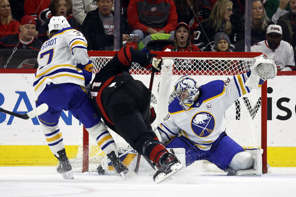 Carolina Hurricanes' Jordan Staal (11) tries to get the puck in the net between Buffalo Sabres' Casey Mittelstadt (37) and goaltender Eric Comrie (31) during the first period of an NHL hockey game in Raleigh, N.C., Saturday, Dec. 2, 2023. (AP Photo/Karl B DeBlaker)