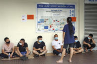 FILE - People wait in line from early morning to receive a shot of COVID-19's vaccine at a clinic in Singapore on June 24, 2021. When Singapore embarked upon its strategy of “living with COVID,” backed by one of the world's leading vaccine programs, the wealthy city-state saw a spike in its rate of infections, leading many to question whether the time was right.(Kyodo News via AP, File)