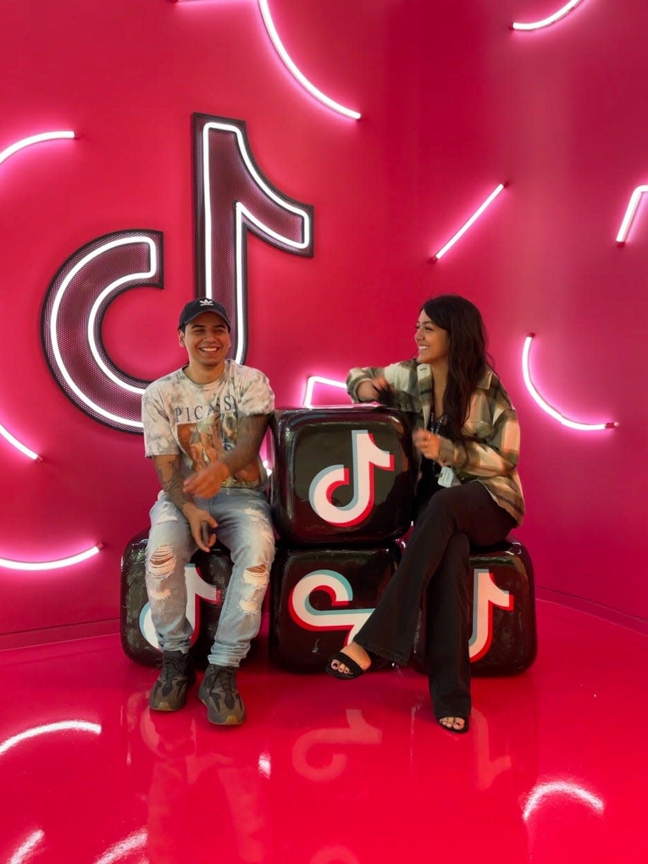 A man and woman sitting next to eachother on boxes with the TikTok logo.