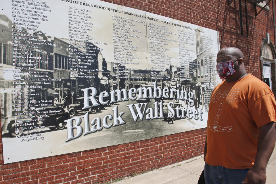 Freeman Culver stands in front of a mural listing the names of businesses destroyed during the Tulsa race massacre in Tulsa, Okla., Monday, June 15, 2020, on the other side of what's historically the city's white-black dividing line from where President Donald Trump will rally Saturday. (AP Photo/Sue Ogrocki)