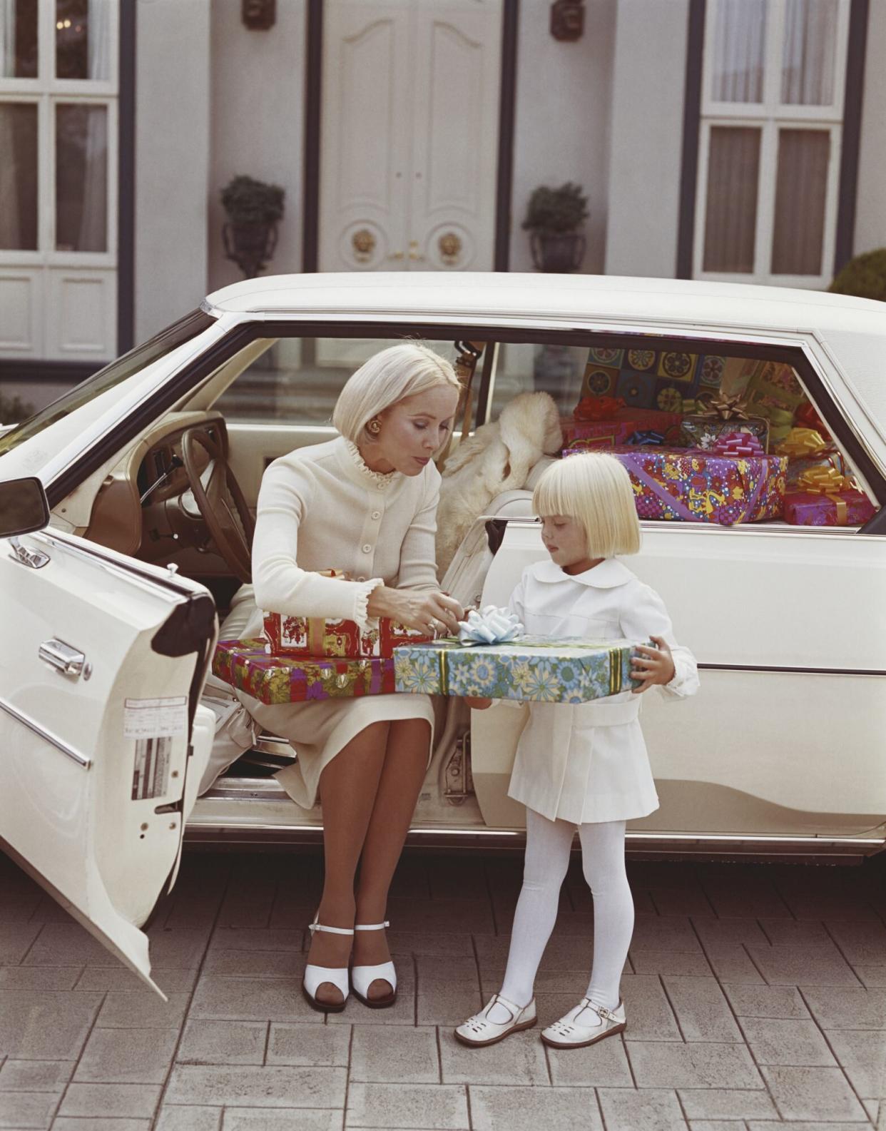 Woman sitting in car and giving gift to daughter