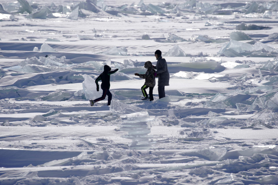 In this Friday, Feb. 22, 2019, photo, people play on the Ice on Lake Superior, starting to pack in along the shore near Duluth, Minn., and attracting explorers and ice fishermen out on to the lake. Access to the mainland ice caves remain CLOSED. Ice continues to move around quite a bit. Over the last few days, open water has been visible from Meyers Beach as well as near Eagle Island. This ice is typically poor quality ice, which reacts poorly to movement due to weak bonding along the fractures. (Brian Peterson/Star Tribune via AP)