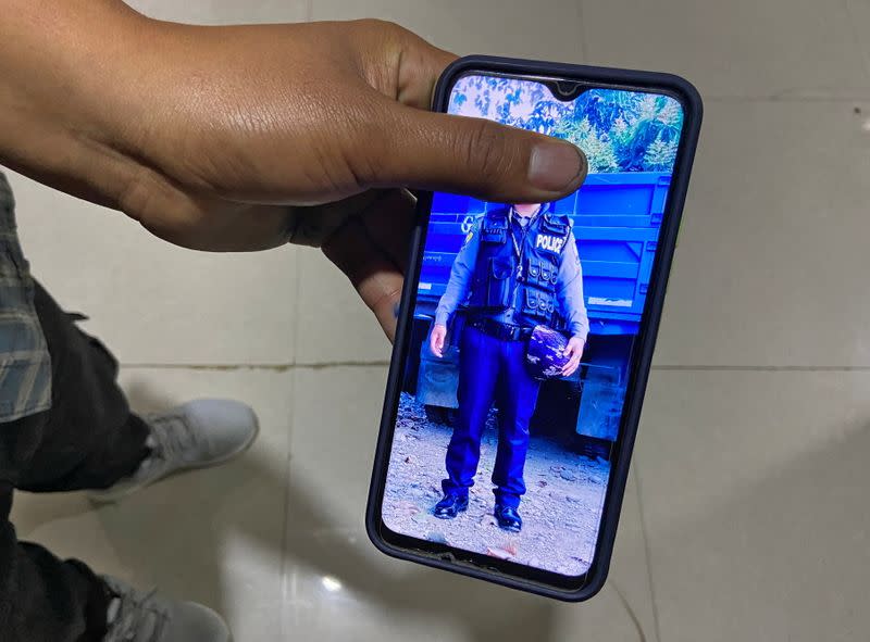 Tha Peng shows his photograph in his phone wearing a police uniform following his interview with Reuters at Champhai town in near the India–Myanmar border