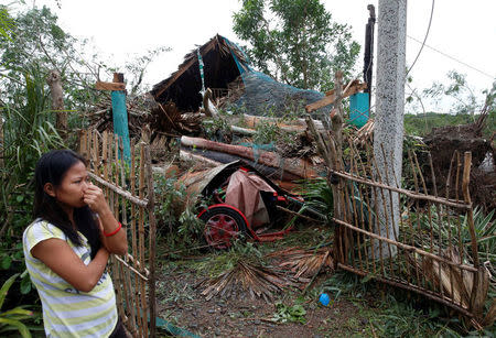 A woman stands outside her house which was damaged by a fallen tree during Typhoon Haima, in Bangui, Ilocos Norte in northern Philippines, October 20, 2016. REUTERS/Erik De Castro
