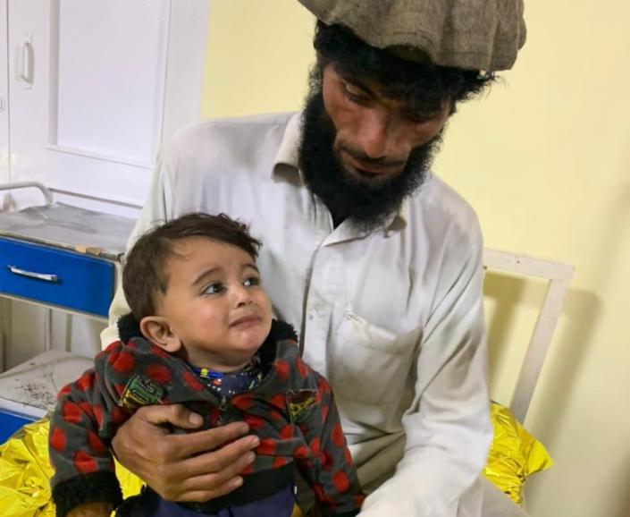 An Afghan man holds a small boy in a hospital