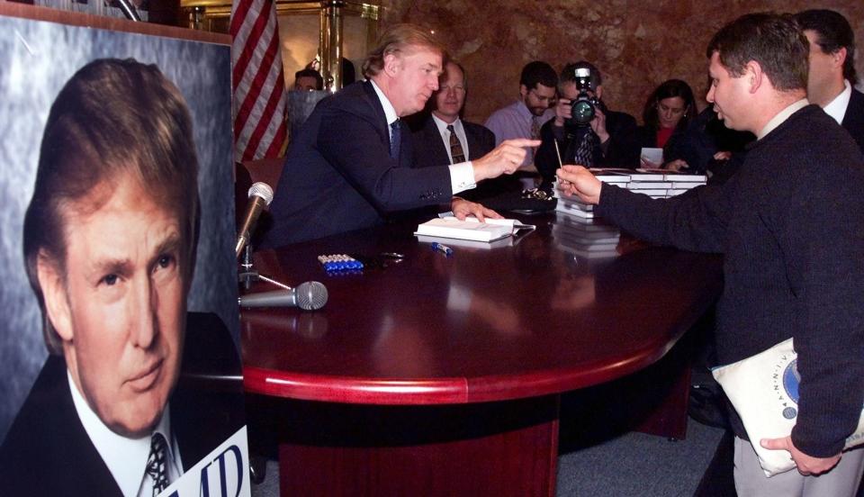 Donald Trump reaches for a pen as he signs a copy of his new book, "Trump: The America We Deserve," at Trump Towers in New York in&nbsp;January 2000.