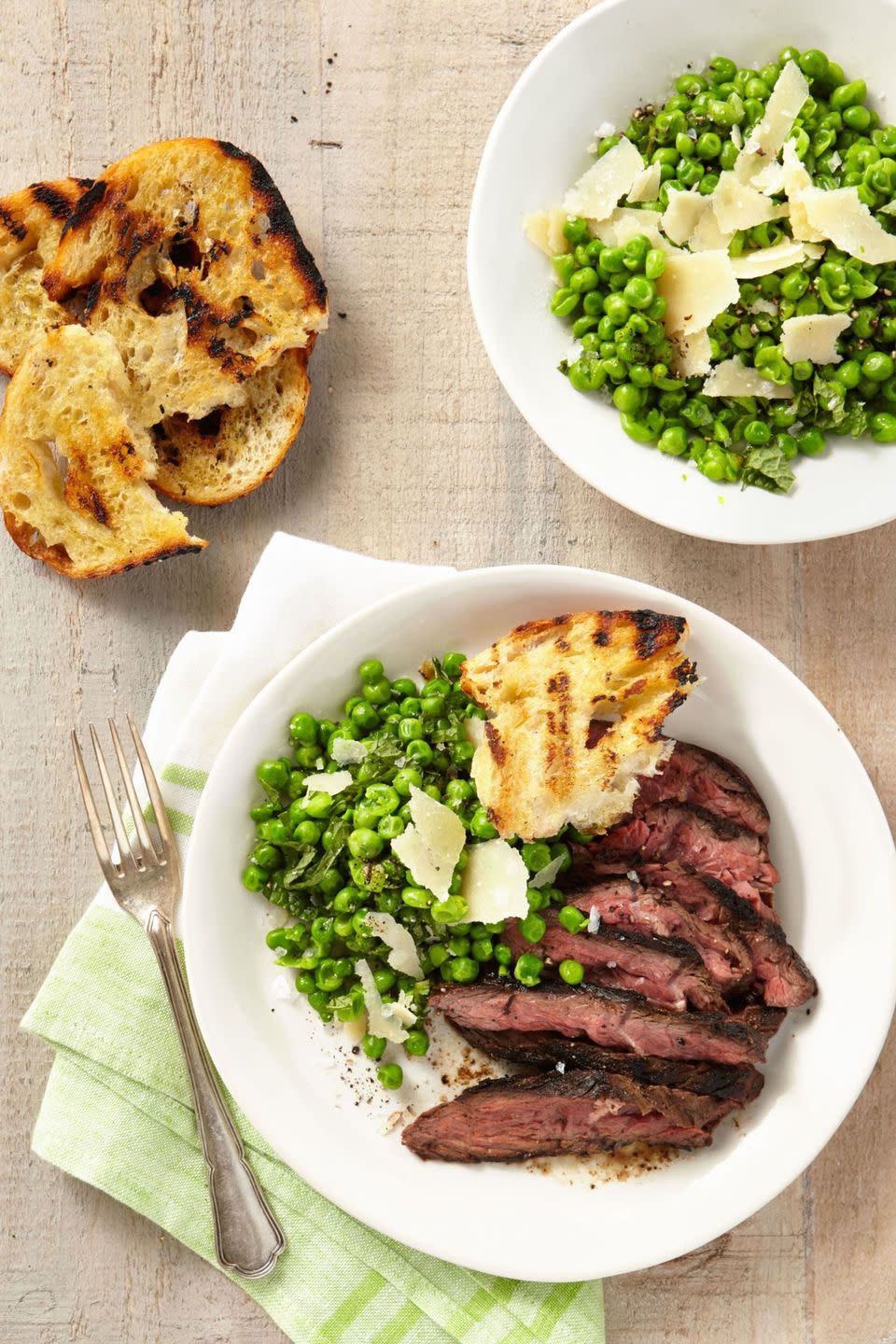 grilled cumin rubbed hanger steak grilled with smashed minty peas and grilled bread on white plate with fork