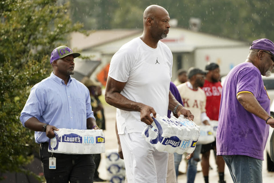 Former NBA basketball player Erick Dampier, joins other volunteers in carrying cases of water to Jackson, Miss., residents during a drive-thru water distribution, Sept. 7, 2022. A boil-water advisory has been lifted for Mississippi's capital, and the state will stop handing out free bottled water on Saturday. But the crisis isn't over. Water pressure still hasn't been fully restored in Jackson, and some residents say their tap water still comes out looking dirty and smelling like sewage. (AP Photo/Rogelio V. Solis)