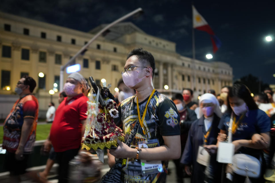 A devotee wearing a face mask holds a replica of the Black Nazarene, a centuries-old charred statue of Jesus Christ, as he joins the "Walk of Faith" procession as part of celebrations for his feast day on Sunday, Jan. 8, 2023, in Manila, Philippines. The annual Black Nazarene feast day which will be held on Jan. 9 draws massive numbers of devotees who pray for the sick and a better life in this predominantly Roman Catholic nation. (AP Photo/Aaron Favila)