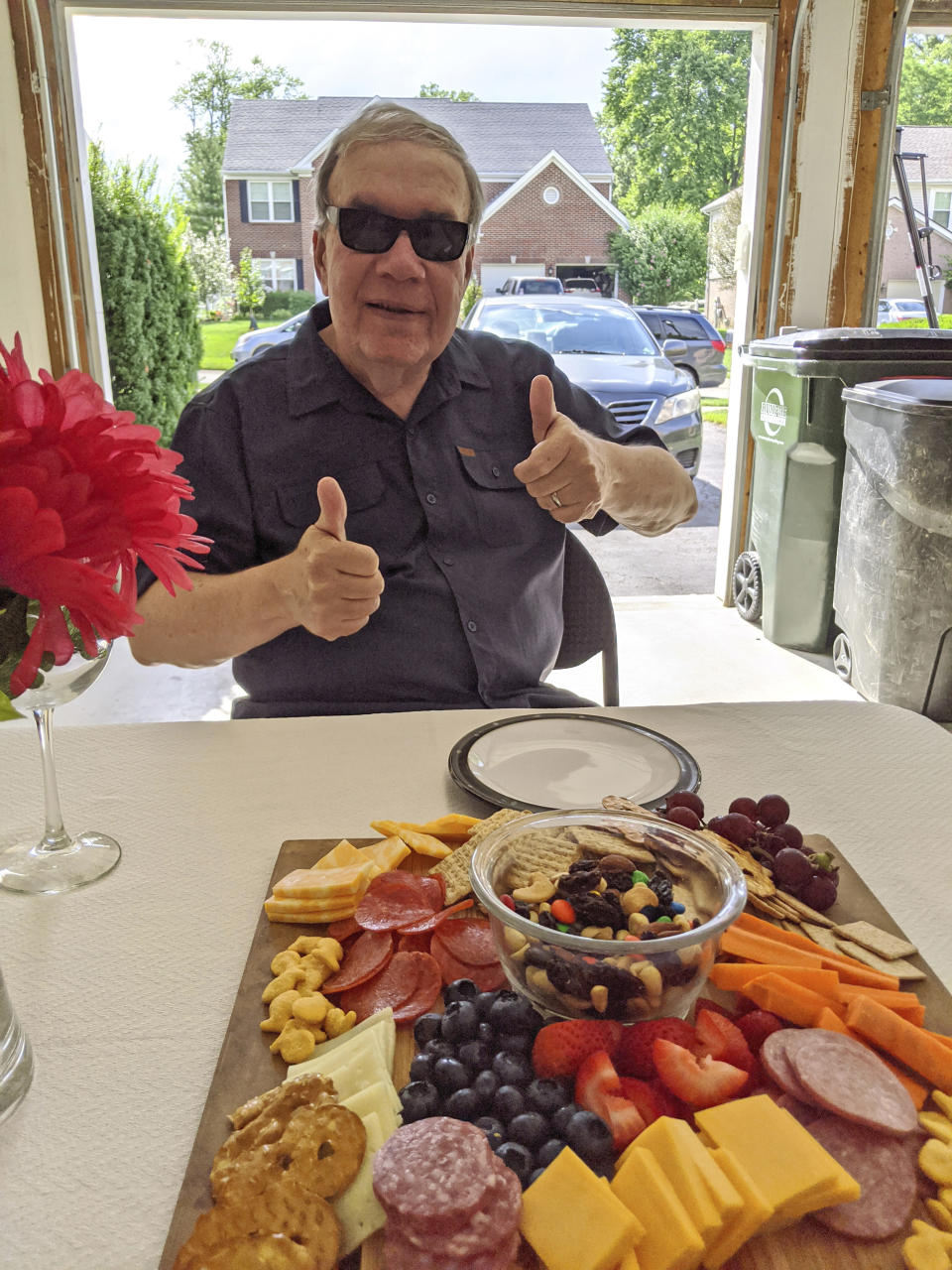 In this photo provided by courtesy of Nancy Peters, Joe Peters gives a thumbs up before enjoying a charcuterie board at a birthday dinner at one of his children's home, Aug. 1, 2020, in Cincinnati. Joe and Nancy Peters had one of their 11 grandchildren over to visit last week as they began “cautiously returning to normal," he says. The pandemic and its isolating restrictions have been especially tough for many of the nation's some 70 million grandparents, many at ages when they are considered most vulnerable to the deadly COVID-19 virus. (Nancy Peters via AP)