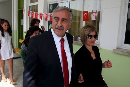 Turkish Cypriot leadership candidate Mustafa Akinci and his wife Meral Akinci walk outside a polling stastion at an elementary school in northern Nicosia, April 26, 2015. REUTERS/Yiannis Kourtoglou