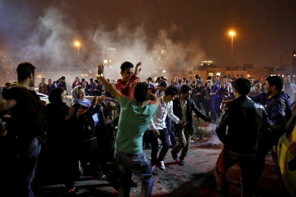 In this picture taken on Tuesday, March 18, 2014, Iranians dance during a celebration, known as “Chaharshanbe Souri,” or Wednesday Feast, marking the eve of the last Wednesday of the solar Persian year, in Pardisan park, Tehran, Iran. The festival has been frowned upon by hard-liners since the 1979 Islamic revolution because they consider it a symbol of Zoroastrianism, one of Iran’s ancient religions of Iranians. They say it goes against Islamic traditions. (AP Photo/Ebrahim Noroozi)