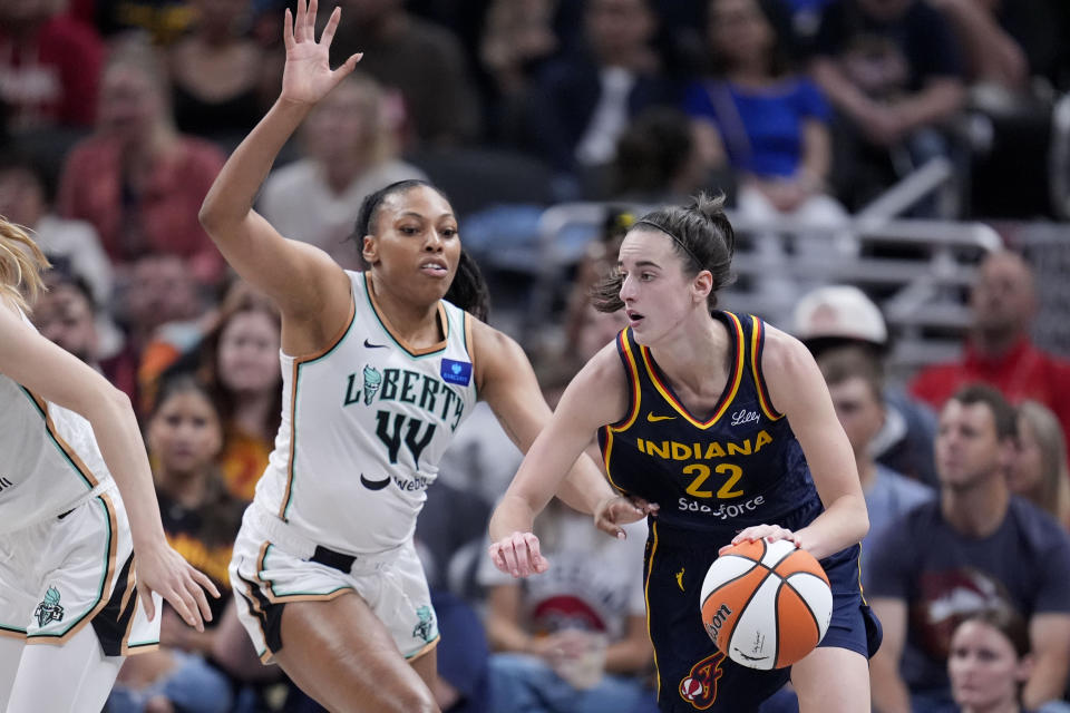 Indiana Fever guard Caitlin Clark (22) drives past New York Liberty forward Betnijah Laney-Hamilton (44) in the first half of a WNBA basketball game, Thursday, May 16, 2024, in Indianapolis. (AP Photo/Michael Conroy)