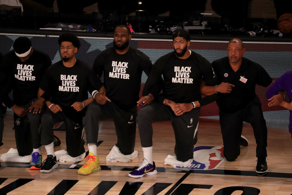 LeBron James #23 and Anthony Davis #3 of the Los Angeles Lakers in a Black Lives Matter Shirt kneel with their teammates during the national anthem. 