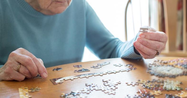 elderly woman doing a puzzle at her table