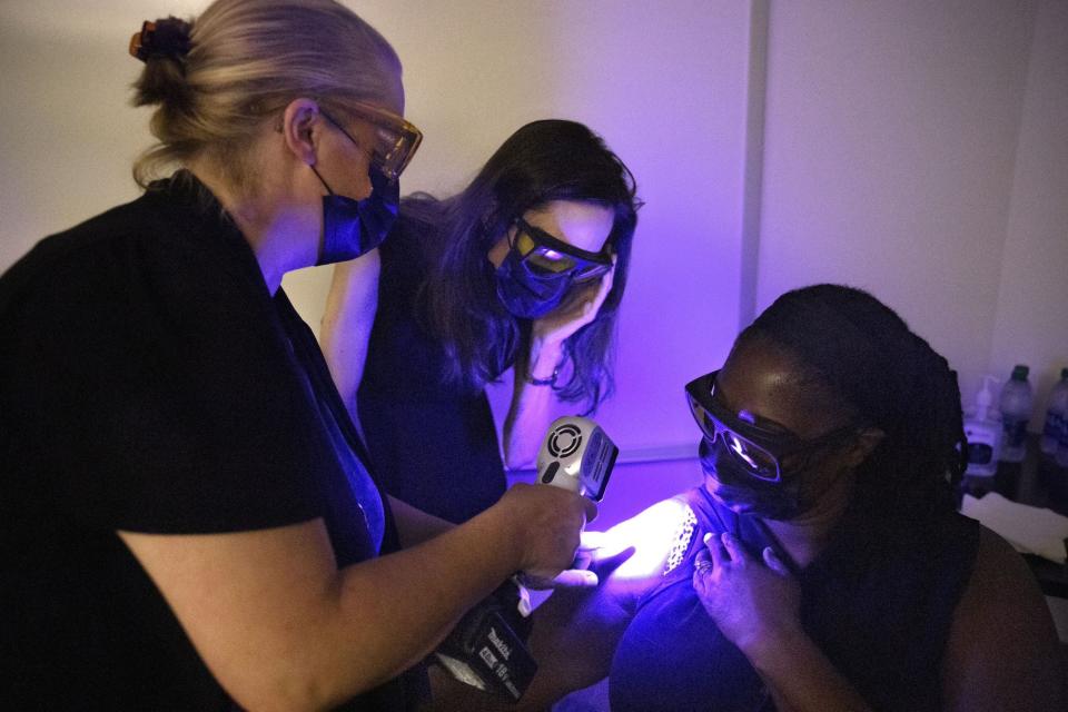 Katherine Scafide using purple light to observe a patient's bruises