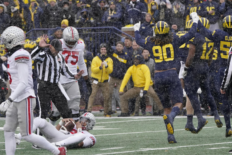 Michigan defensive end Mike Morris (90) runs off the field after Ohio State quarterback C.J. Stroud, left, was sacked during the first half of an NCAA college football game, Saturday, Nov. 27, 2021, in Ann Arbor, Mich. (AP Photo/Carlos Osorio)