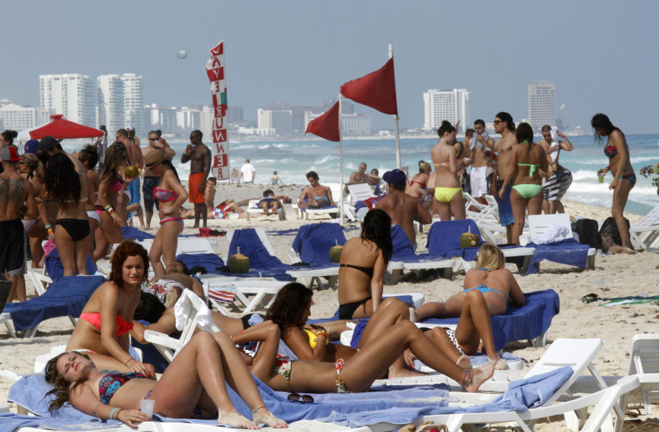 FILE - In this March 10, 2012 file photo, people fill the beach during Spring Break in Cancun, Mexico. Almost 7 million international tourists visit this stretch of coast every year, many of whom arrive at the Cancun airport and are bused or drive down the Riviera Maya. (AP Photo/Israel Leal, File)