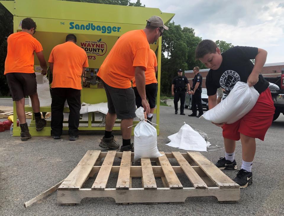 Ontario County crews, with help from Canandaigua football players, bag and load sandbags for residents devastated by flooding.
