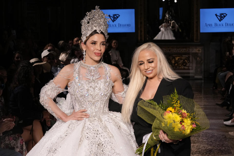 Wearing an April Black Diamond creation, Emma Coronel, wife of Joaquin "El Chapo" Guzman, poses for a photo with the designer during a Spring Summer 2025 collection presentation, in Milan, Italy, Sunday, Sept. 22, 2024. (AP Photo/Antonio Calanni)