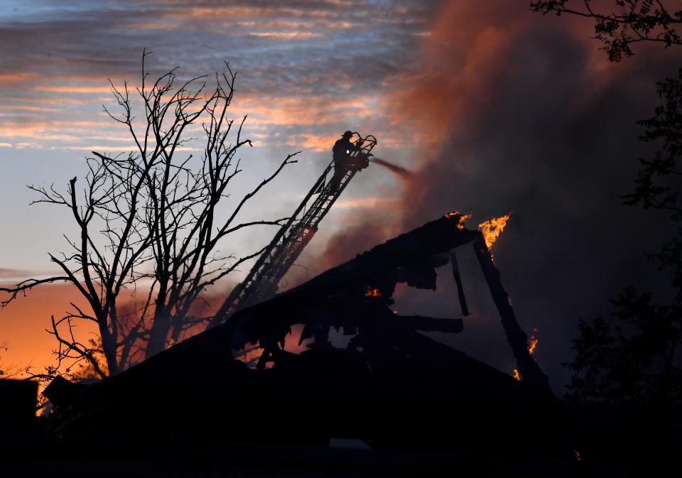 An Abilene firefighter sprays water from a ladder over the remains of St. Ann's Hospital as the sun rises in the background Tuesday.