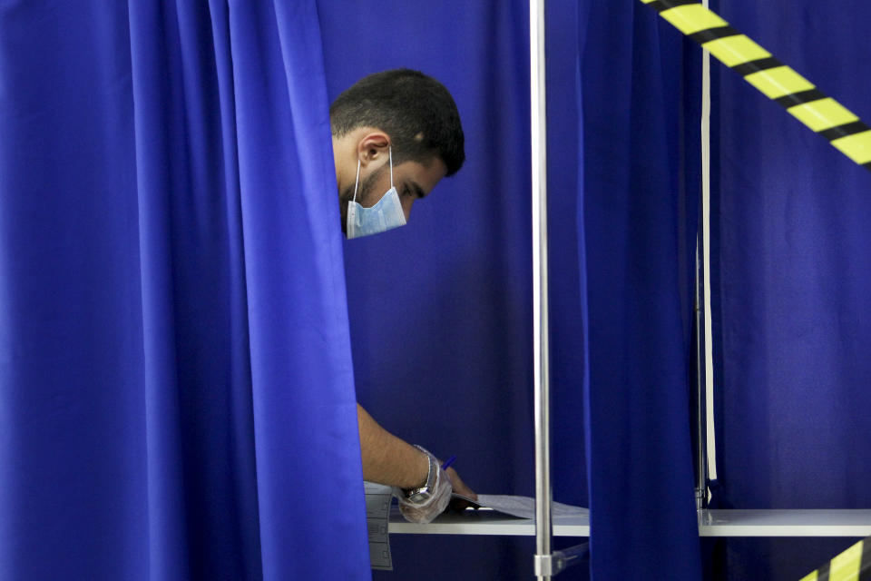 A Chechen man reads his ballots in a voting booth at a polling station during the Parliamentary elections in Grozny, Russia, Saturday, Sept. 18, 2021. Sunday will be the last of three days voting for a new parliament, but there seems to be no expectation that United Russia, the party devoted to President Vladimir Putin, will lose its dominance in the State Duma. (AP Photo/Musa Sadulayev)