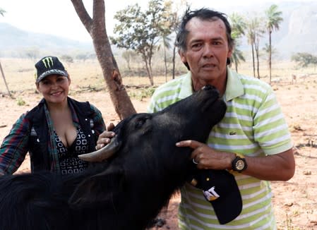 Farmers Ludwing Weber and his wife Viviana pose for a picture with a young buffalo at the Esperanza ranch in the area where wildfires have destroyed hectares of forest near Robore