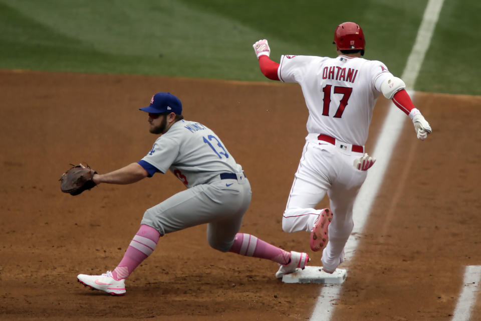 Los Angeles Angels designated hitter Shohei Ohtani, right, beats the throw to Los Angeles Dodgers first baseman Max Muncy for an infield single during the first inning of a baseball game in Anaheim, Calif., Sunday, May 9, 2021. (AP Photo/Alex Gallardo)