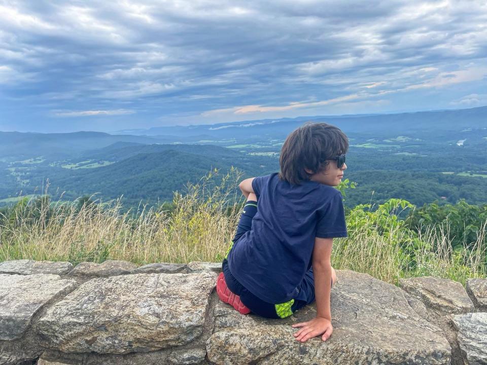 Boy sitting on edge of rocks in Shenandoah national park 