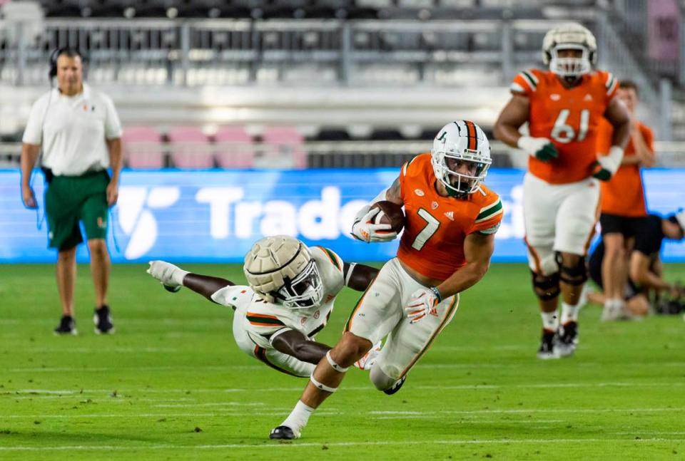 Miami Hurricanes wide receiver Xavier Restrepo (7) runs with the ball as Miami Hurricanes linebacker Wesley Bissainthe (31) tries to tackle during the first quarter of their spring game at DRV PNK Stadium on Friday, April 14, 2023, in Fort Lauderdale, Fla.