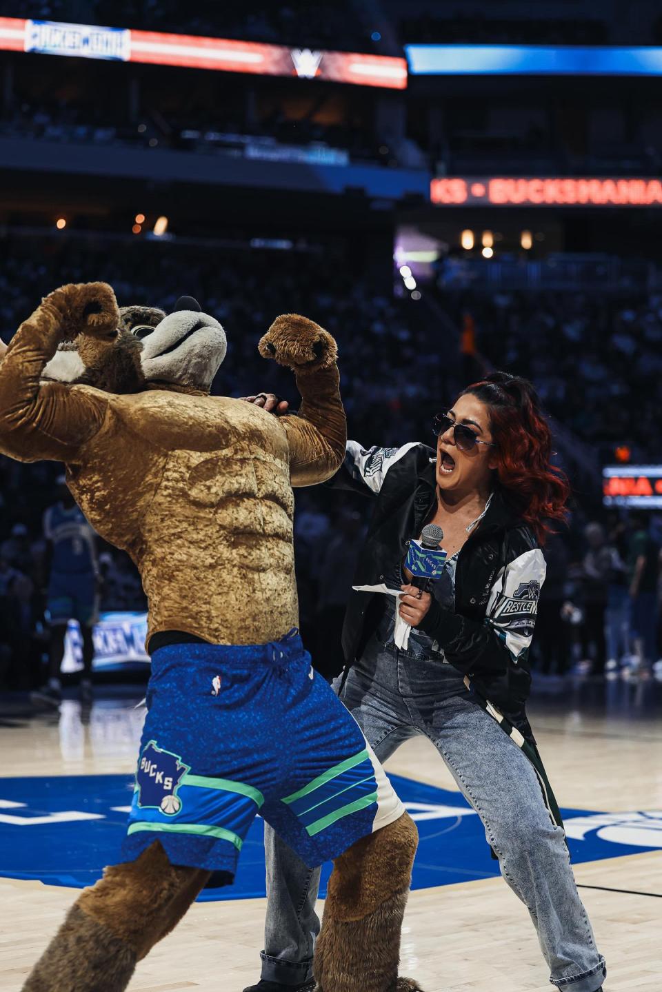 WWE superstar Bayley leads the "Flex Cam" with Bango during the Milwaukee Bucks game on Thursday, March 21, 2024. She called Bango the "Undisputed No. 1 mascot in the NBA." Bayley will headline "SmackDown" Friday at Fiserv Forum in Milwaukee.