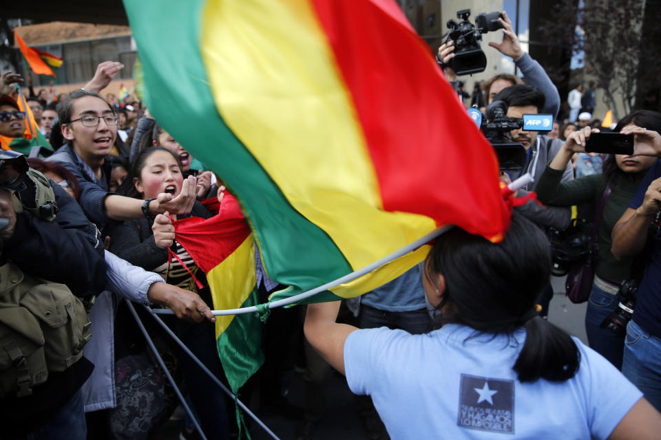 Supporters of opposition presidential candidate Carlos Mesa, a former president, top, use their flag to hit a supporter of Bolivian President Evo Morales, who is running for reelection, his fourth term, as rival groups gather outside the Supreme Electoral Court where election ballots are being counted in La Paz, Bolivia, Monday, Oct. 21, 2019. A sudden halt in release of presidential election returns led to confusion and protests in Bolivia on Monday as opponents suggested officials were trying to help Morales avoid a risky runoff. (AP Photo/Jorge Saenz)