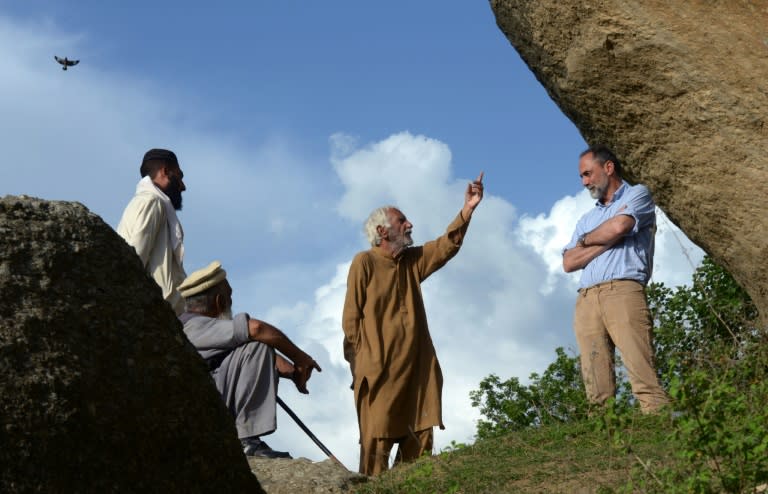 Italian archaeologist Luca Maria Olivieri (R) listens to Pakistani historian Parvesh Shaheen (C) beside the seventh century rock sculpture of a seated Buddha in Swat