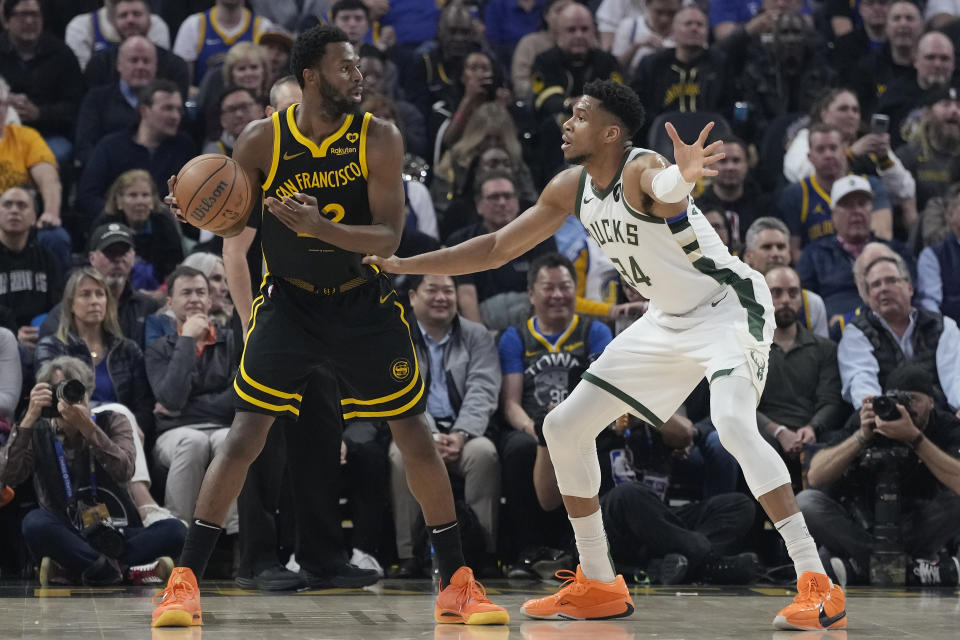 Golden State Warriors forward Andrew Wiggins, left, looks to pass the ball while being defended by Milwaukee Bucks forward Giannis Antetokounmpo during the first half of an NBA basketball game in San Francisco, Wednesday, March 6, 2024. (AP Photo/Jeff Chiu)