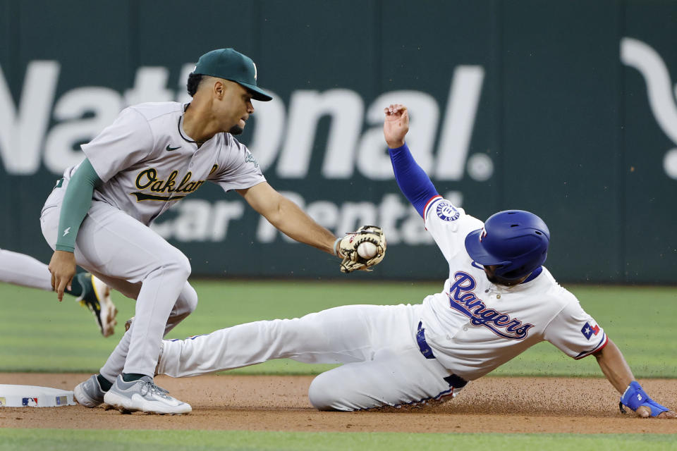 Texas Rangers' Marcus Semien, right, steals second base as Oakland Athletics shortstop Darell Hernaiz makes the late tag during the first inning of a baseball game Thursday, April 11, 2024, in Arlington, Texas. (AP Photo/Michael Ainsworth)