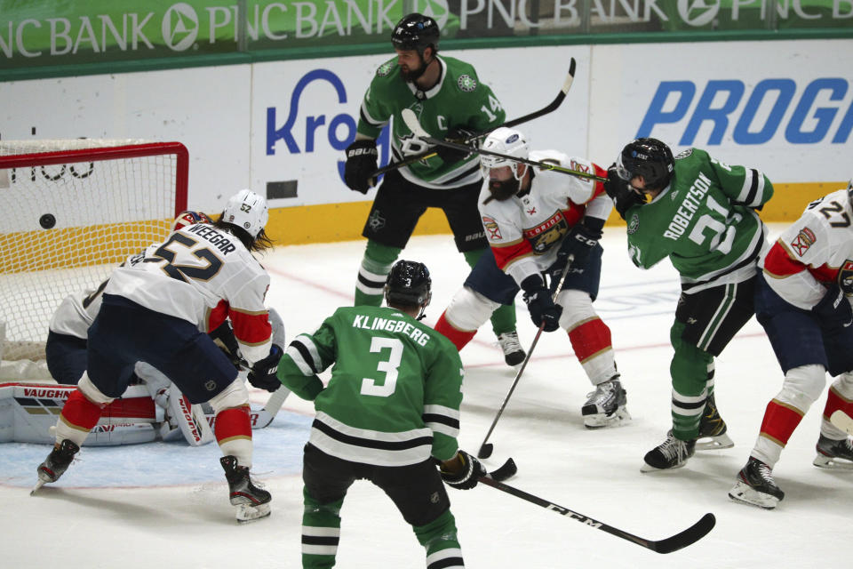 Dallas Stars left wing Jason Robertson (21) fires a shot past Florida Panthers defenseman MacKenzie Weegar (52) and defenseman Radko Gudas (7) to score during the first period of an NHL hockey game Tuesday, April 13, 2021, in Dallas. (AP Photo/Richard W. Rodriguez)