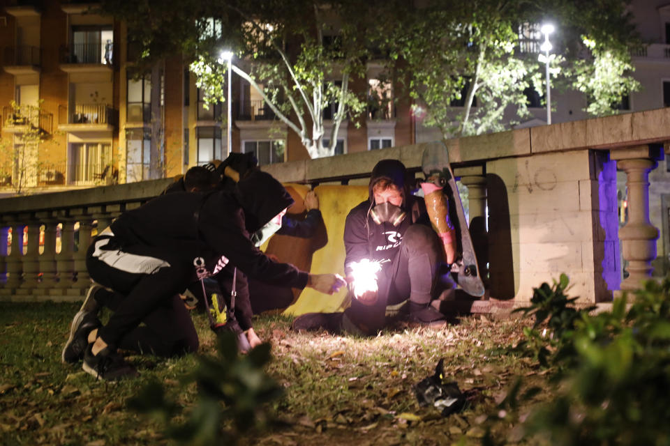 Protestors light a firecracker to throw at police during clashes in Barcelona, Spain, Wednesday, Oct. 16, 2019. Spain's government said Wednesday it would do whatever it takes to stamp out violence in Catalonia, where clashes between regional independence supporters and police have injured more than 200 people in two days. (AP Photo/Emilio Morenatti)