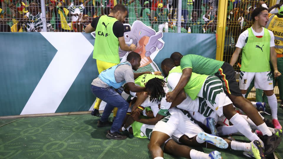 Players and coaching staff celebrate after Cameroon scores the late winner. - Kenzo Tribouillard/AFP/Getty Images