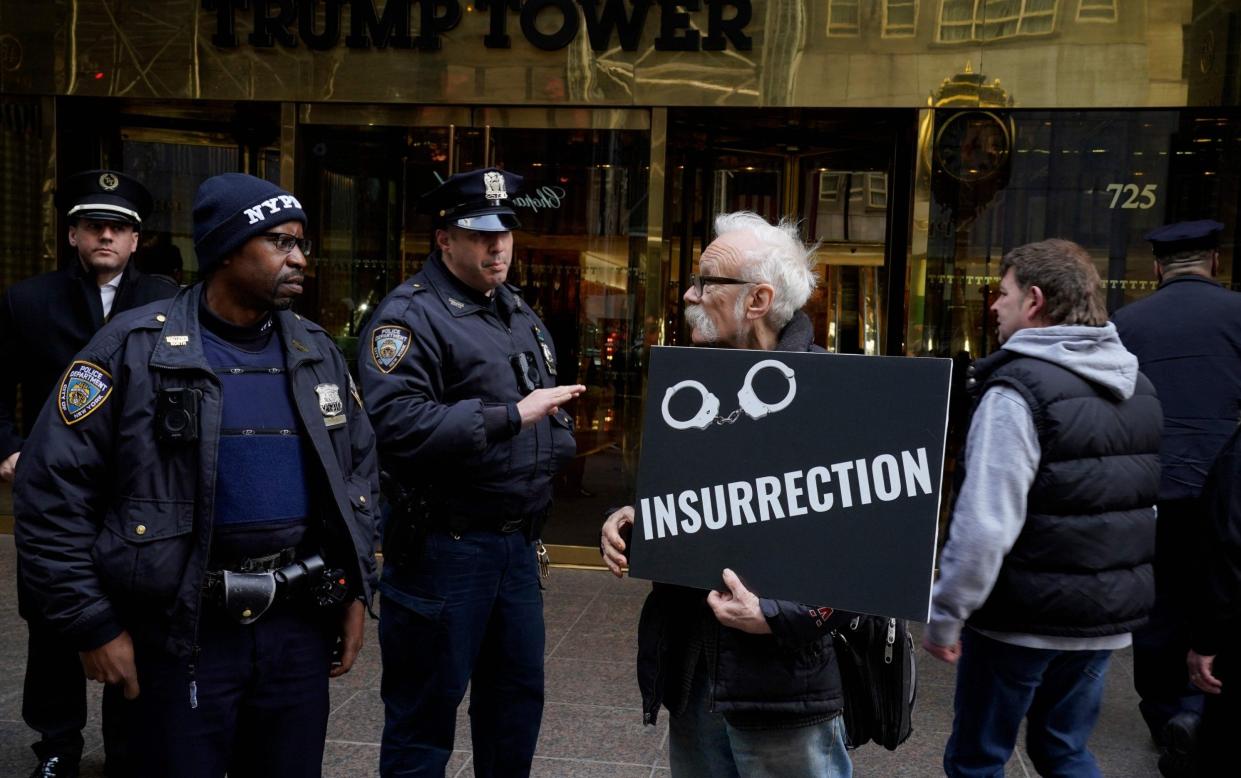 Officers talk to a protester in front of Trump Tower, in New York City, on Friday - Timothy A Clary/AFP