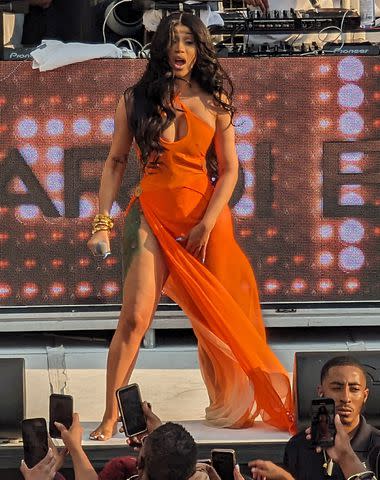 <p>Brian Prahl / SplashNews.com</p> Cardi B stuns in flowing orange swim cover up as she performs in Las Vegas last weekend