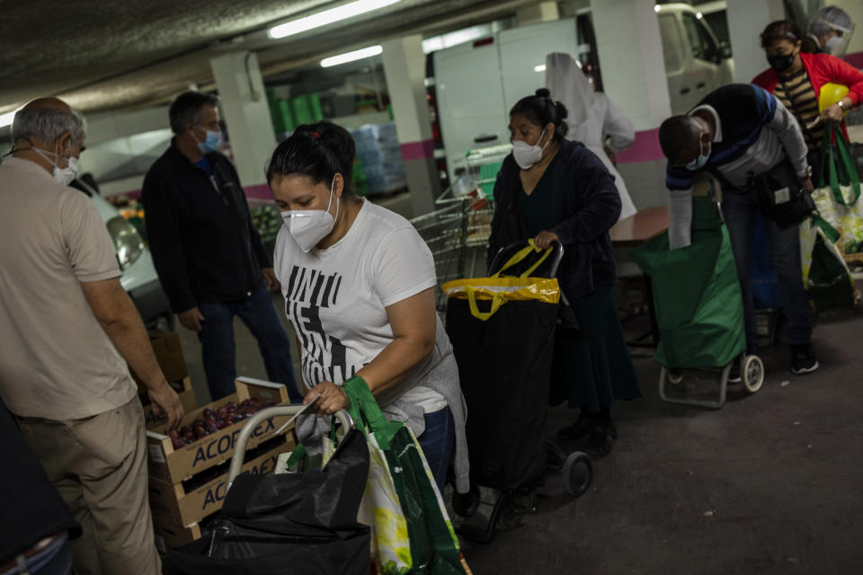 Erika Oliva, 39, collect food donations at a servants of Jesus congregation center in Madrid, Spain, Thursday, Oct. 8, 2020. Oliva spends at least three hours a week standing in line at a soup kitchen. She spends a couple more at the social worker's office with her 8-year-old son, who has autism. She waits on the phone to the health center or when she wants to check if her application for a basic income program will get her the promised 1,015 euros ($1,188). (AP Photo/Bernat Armangue)