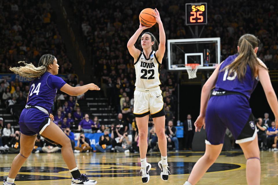 Iowa Hawkeyes guard Caitlin Clark shoots the ball as Holy Cross guard Simone Foreman, left, and guard Cara McCormack, right, look on.