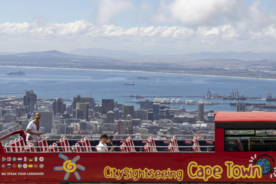 An open-air double decker sightseeing bus stops on the slopes of Table Mountain, overlooking the city of Cape Town, South Africa, Friday March, 20, 2020 Anxiety rose in Africa's richest nation Friday as South Africa announced coronavirus cases jumped to 202, the most in the sub-Saharan region, while the country's largest airport announced that foreigners would not be allowed to disembark. And state-owned South African Airways suspended all international flights until June. For most people, the new coronavirus causes only mild or moderate symptoms, such as fever and cough. For some, especially older adults and people with existing health problems, it can cause more severe illness, including pneumonia. (AP Photo)