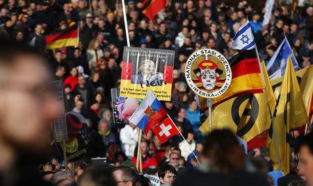 Supporters of the anti-Islam movement Patriotic Europeans Against the Islamisation of the West (PEGIDA) hold posters depicting German Chancellor Angela Merkel during a demonstration in Dresden, Germany, February 6, 2016. REUTERS/Hannibal Hanschke