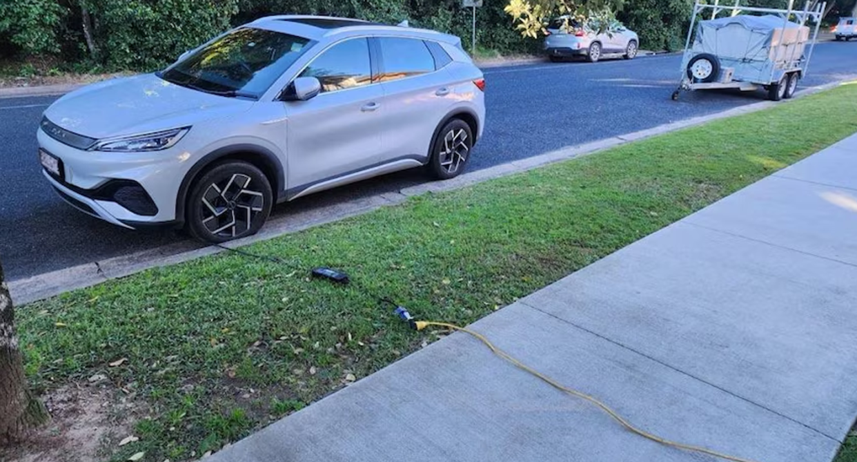 An EV charging from the street in Sawtell, which had a cord that ran across the paved footpath, over an adjacent lawn, all the way to the top story of a block of units in Sawtell. Source: ABC